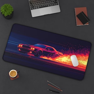 May include: A red Dodge Challenger muscle car driving on a dark blue background with a trail of orange flames behind it. The car is on a black and white mousepad with a white computer mouse.