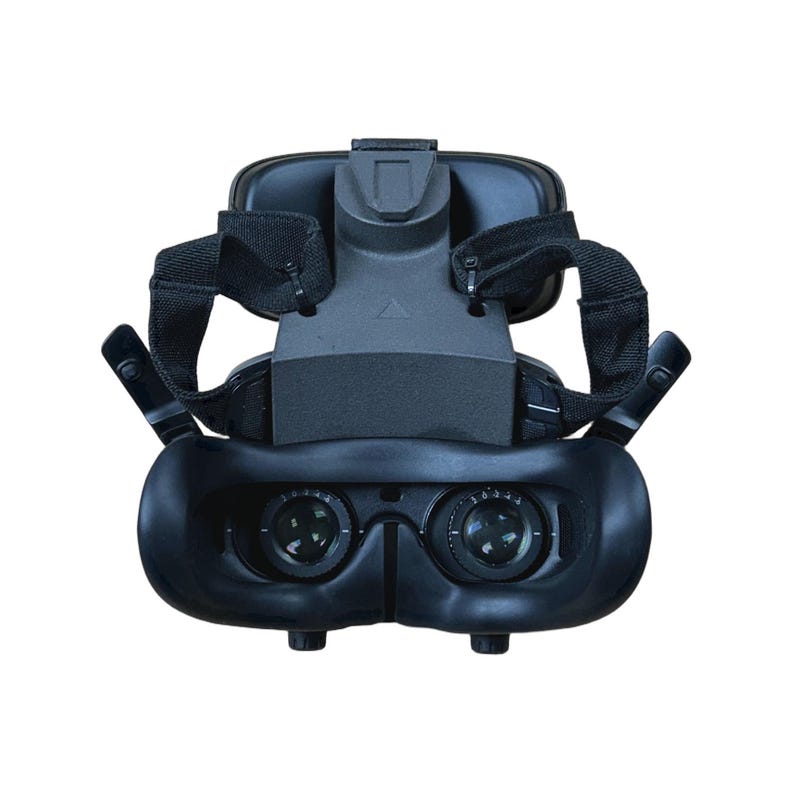 May include: A black virtual reality headset with adjustable straps and dual lenses. The headset features a head mount and a central support structure. The lenses are visible at the bottom of the headset.