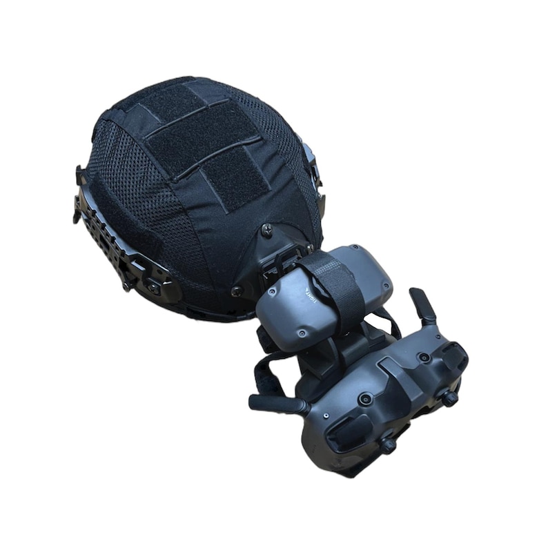 May include: Black tactical helmet with mesh covering and velcro patches. Attached is a gray and black virtual reality headset with adjustable straps and antennas. The helmet appears to be designed for military or law enforcement use.