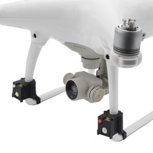 May include: White drone with gray camera and black landing gear. The drone has the word "Phantom" printed on the body. The camera is mounted on a gimbal. The drone has four propellers and is designed for aerial photography and videography.