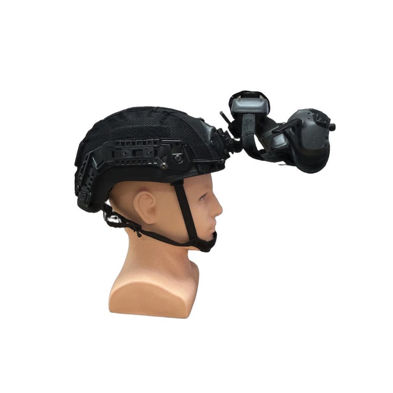 May include: Black tactical helmet with attached night vision goggles. The helmet features a mesh covering and various mounting points. The night vision system is mounted on a bracket and strap system. The helmet is displayed on a mannequin head.
