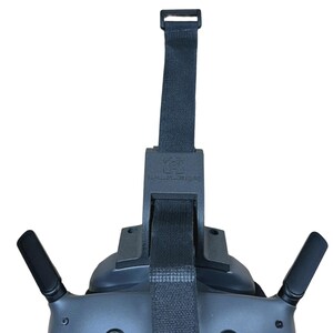 May include: A dark gray VR headset with a black adjustable strap and two black antennas. The strap has a buckle and a logo. The headset is designed for virtual reality experiences.