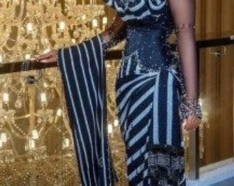 Könnte beinhalten: Ein formelles Kleid mit einem schwarz-weißen Streifenmuster. Das Kleid hat ein eng anliegendes Oberteil, transparente Ärmel und eine passende Kopfbedeckung. Das Kleid ist mit Perlen verziert und wird mit hochhackigen Sandalen kombiniert. Der Hintergrund umfasst einen dekorativen Kronleuchter.