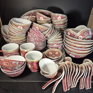 May include: A collection of red and white porcelain dishware with intricate floral patterns. The set includes bowls, plates, cups, and spoons. The rims are decorated with gold trim and the bowls have a white interior.