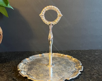 May include: Silver serving tray with a decorative handle and a scalloped edge. The tray has an ornate design.