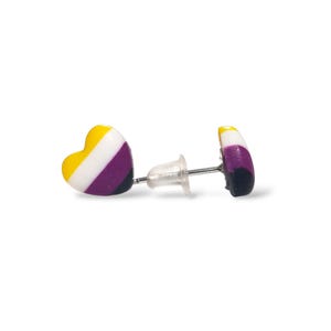 May include: A pair of heart-shaped stud earrings. Each earring features a yellow, white, purple, and black design. The earrings have a post and backing for secure wear. The earrings are set against a white background.