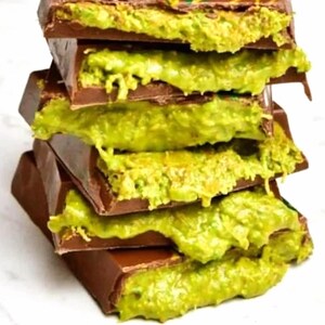以下が含まれることがあります： 鮮やかな緑色のフィリングが入ったチョコレートバーのスタック。チョコレートは濃厚な茶色で、フィリングはピスタチオクリームのようです。バーは互いの上に積み重ねられており、視覚的に魅力的なおやつになっています。