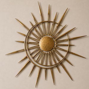 Peut inclure: Une sculpture murale circulaire composée d'un disque central doré entouré de deux anneaux concentriques. De nombreuses pointes métalliques effilées de longueurs variées rayonnent vers l'extérieur, formant un motif en forme de soleil.