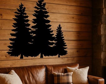 May include: A black silhouette of three pine trees is mounted on a wooden wall. The trees are of varying heights, with the tallest in the center. The wall is made of horizontal wooden planks. A brown leather sofa with pillows and a blanket is in front of the wall.
