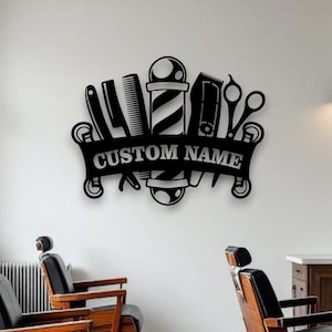 May include: A black metal wall sign featuring a central barber pole flanked by a straight razor, a comb, hair clippers, and scissors. A horizontal banner across the centre displays the text CUSTOM NAME in bold, capitalised, sans-serif letters.