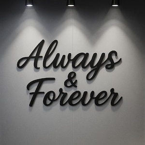 May include: Black cursive lettering on a gray wall reads "Always & Forever." The words are in a stylish script font, with the ampersand symbol between them. The wall is lit by three overhead spotlights.