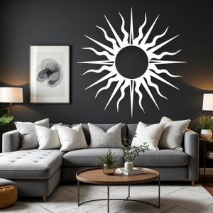 May include: A white sunburst wall decoration is fixed to a dark grey wall above a grey sectional sofa. The sunburst features a central circle with stylized rays. A framed abstract art piece and lamps are positioned near the sofa.