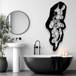 May include: A contemporary bathroom in monochrome. A striking black wall art piece shows a stylized hand reaching out. The room features a circular mirror, a white pedestal sink, and a black bathtub. A potted plant and candles provide decoration.