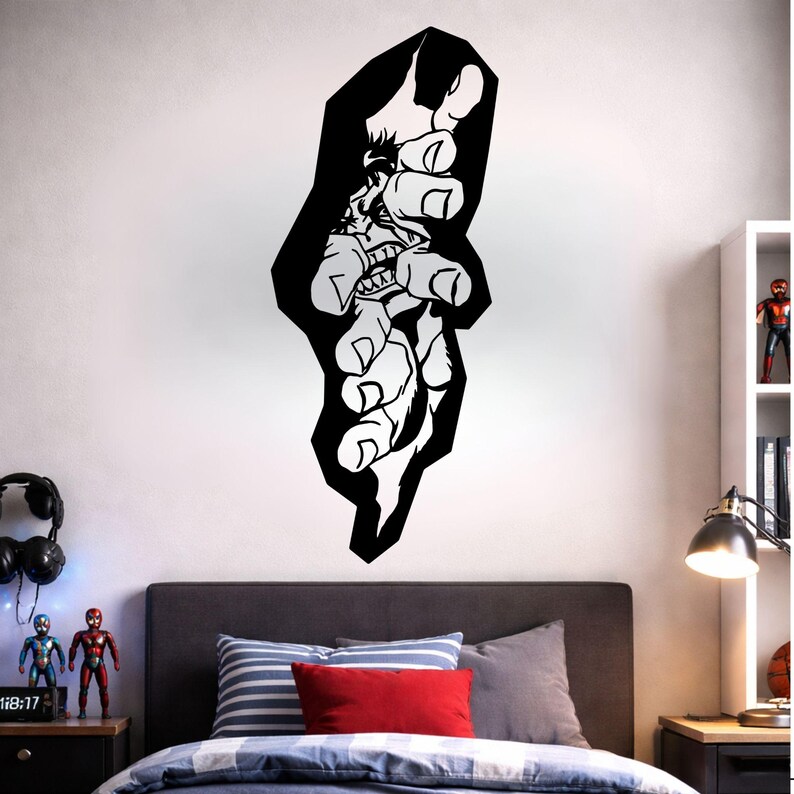 May include: A black and white wall sticker depicting a stylized hand reaching out. The design incorporates a detailed illustration of a face within the hand, with sharp teeth and a menacing expression. The sticker is applied to a white wall above a bed.