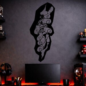 May include: A black and grey wall art piece showing a stylized hand reaching out. The artwork features a detailed illustration of a hand with a menacing face within the hood. The design is mounted on a dark grey wall, creating a striking contrast.