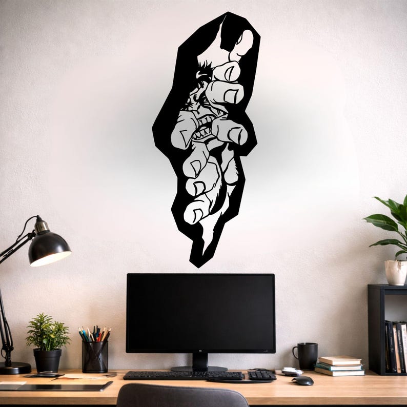 May include: Black and white wall art depicting a stylized hand reaching out. The artwork has a bold, graphic design with a cartoonish face in the center of the hand. The art is mounted on a white wall above a desk.