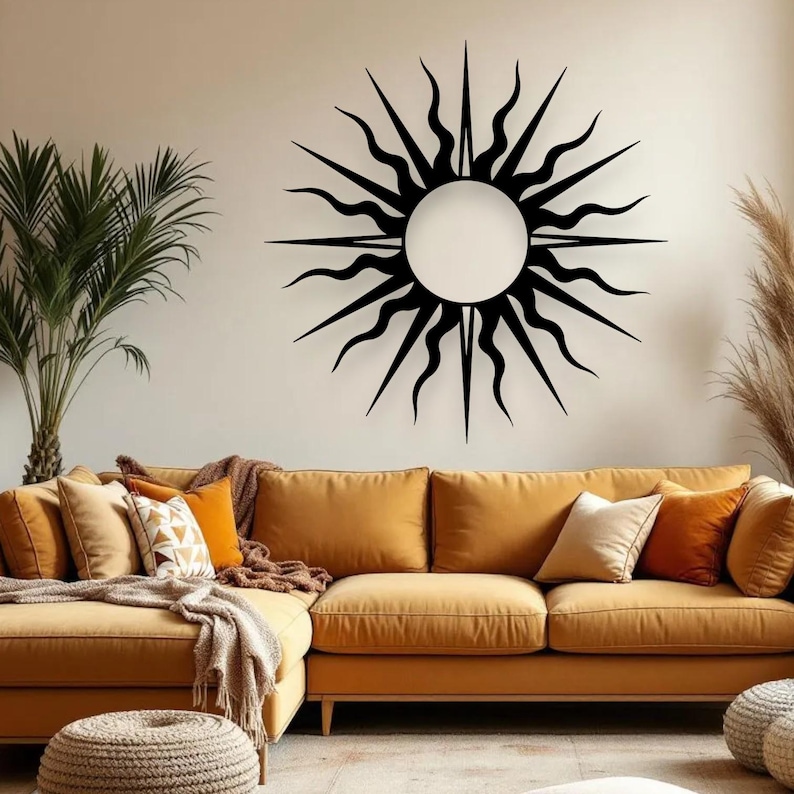 May include: Black metal sunburst wall art with a circular centre and radiating spikes. The sunburst is mounted on a neutral-coloured wall above a mustard-coloured sectional sofa with decorative cushions.