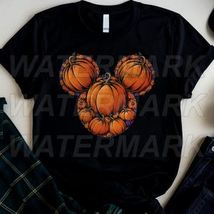 May include: A black short-sleeved t-shirt featuring a graphic print of multiple orange pumpkins arranged to form the shape of a mouse head silhouette. The design includes smaller pumpkins and purple accents nestled between the larger pumpkin shapes.