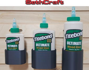 May include: Three dark gray wood glue holders, each holding a bottle of Titebond III Ultimate Wood Glue. The bottles have green caps and labels. Text at the top reads "Wood Glue Holder" and "SethCraft".