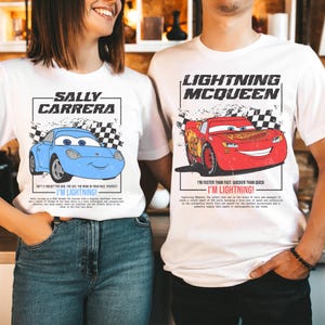 May include: White t-shirts featuring cartoon cars. One shirt displays a blue car with "SALLY CARRERA" and "I'M LIGHTNING!" text. The other shirt shows a red car with "LIGHTNING MCQUEEN" and "I'M LIGHTNING!" text.