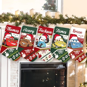 May include: Five Christmas stockings, each with a different name embroidered: Thomas, Henry, Jackson, James, and Brian. Each stocking features a Cars character wearing a Santa hat. The stockings are red, green, and white, with festive patterns.