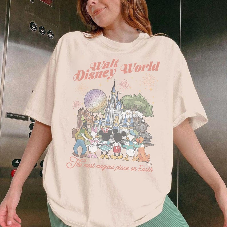 Puede incluir: Camiseta color crema con un gr&aacute;fico colorido de personajes y lugares emblem&aacute;ticos de Disney World. El texto "Walt Disney World" y "The most magical place on Earth" est&aacute; impreso en un estilo vintage.