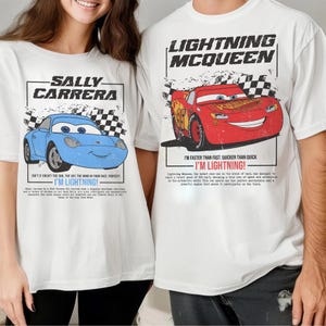 May include: White t-shirts featuring cartoon car graphics. One shirt displays a blue car with "SALLY CARRERA" and "I'M LIGHTNING!" text. The other shirt shows a red car with "LIGHTNING MCQUEEN" and "I'M LIGHTNING!" text.