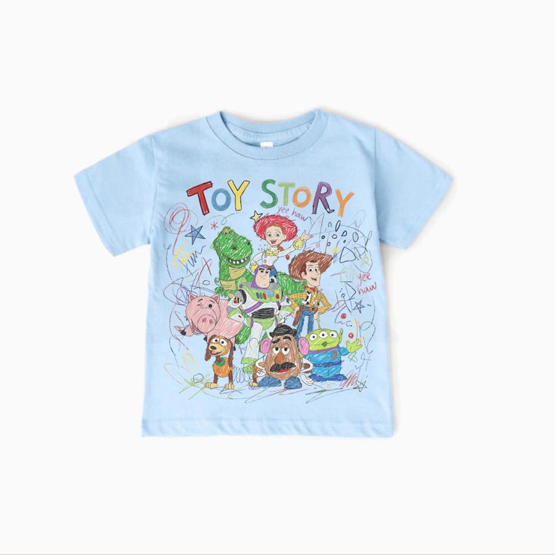 May include: A light blue t-shirt featuring a colorful, hand-drawn style graphic of characters from the animated film "Toy Story." The text "TOY STORY" is at the top in rainbow colors. The shirt is a short-sleeved crew neck.