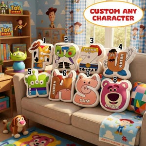 May include: A selection of Toy Story character pillows shaped like letters, displayed on a beige sofa. The room features Toy Story wallpaper and curtains. The pillows, with names such as Frank, Robert, Zoana, Uriah, Noah, Henry, Sam, and Olivia, are part of a themed collection.