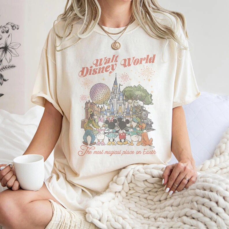 Puede incluir: Camiseta color crema con un gr&aacute;fico colorido de personajes y lugares emblem&aacute;ticos de Disney World. El texto "Walt Disney World" y "The most magical place on Earth" est&aacute;n impresos encima y debajo del gr&aacute;fico.