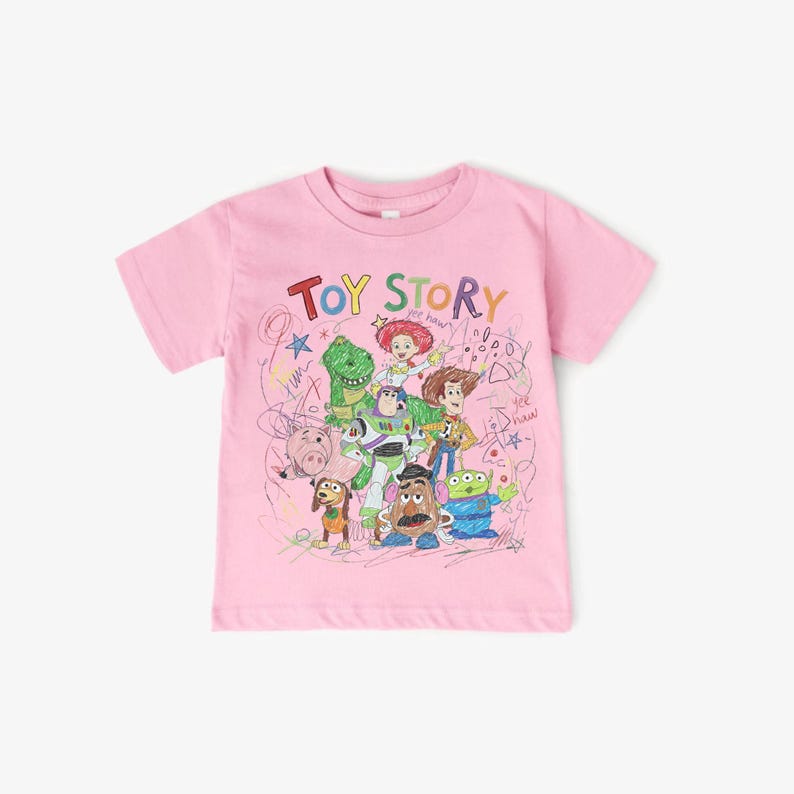 May include: Pink short-sleeved t-shirt featuring the text "TOY STORY" above a colorful illustration of characters from the animated movie. The design includes Woody, Buzz Lightyear, and other characters. The shirt is made of a soft material.