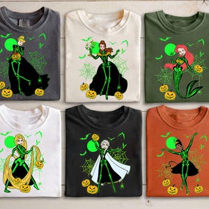 May include: Six t-shirts with Halloween-themed designs. Each shirt features a princess character with a skeleton design, spiderwebs, bats, and jack-o'-lanterns. The shirts are in various colors, including gray, white, green, black, and orange.