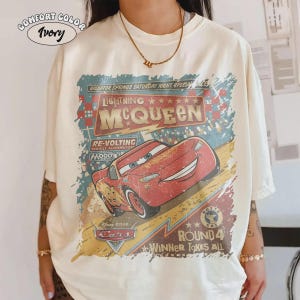 May include: Ivory Comfort Color t-shirt featuring a distressed graphic of Lightning McQueen from the Disney Pixar Cars movie. The design includes text that reads "Radiator Springs Saturday Night Special Race" and "Round 4 Winner Takes All."