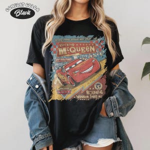 May include: Black t-shirt featuring a distressed graphic of Lightning McQueen from the movie Cars. The graphic includes text that reads "Lightning McQueen" and "Radiator Springs." The shirt is labeled "Comfort Color Black."