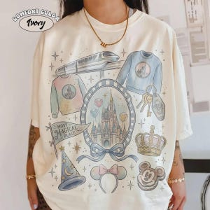 Pode incluir: Camiseta Comfort Colors marfim com um design extravagante com um castelo, trem, suéter, chaves e outros gráficos temáticos. A camisa inclui o texto "Most Magical Place".