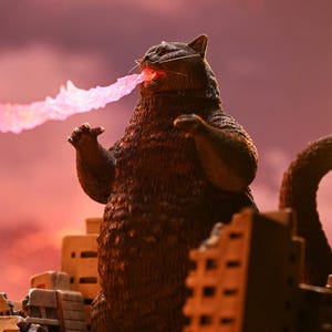 May include: A large, brown, furry cat-like monster with a pink beam of energy coming from its mouth. The monster is standing in front of a destroyed city.