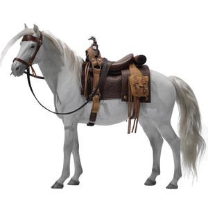 Op de afbeelding: Een wit paard met een bruin leren zadel, hoofdstel en teugels. Het zadel heeft een gewatteerde zitting en een klein tasje met franjes. De manen en staart van het paard zijn lang en wit.