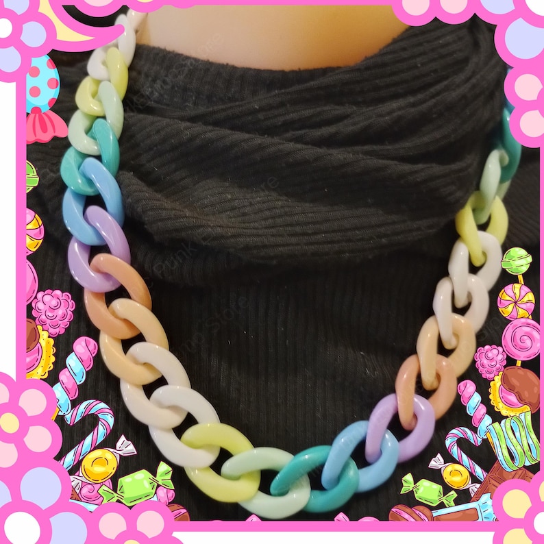 Puede incluir: Un collar de cadena colorido con eslabones ovalados grandes en tonos pastel de blanco, amarillo, verde, azul, morado y melocot&oacute;n. El collar se usa sobre un fondo negro. El collar grueso es una pieza llamativa.