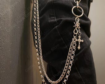 May include: Silver-toned chain accessory with multiple strands, a large ring, and a cross pendant. The chain features a barbed wire design and is attached to a belt loop. The accessory is shown against a black background.
