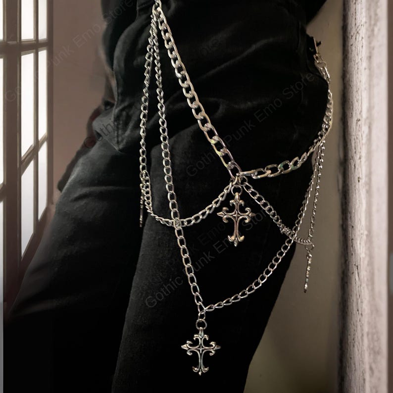 May include: Silver-toned chain accessory with multiple strands and dangling cross pendants. The chains are attached to a belt loop, creating a layered effect. The accessory is designed to be worn on the leg, adding a gothic or punk aesthetic.