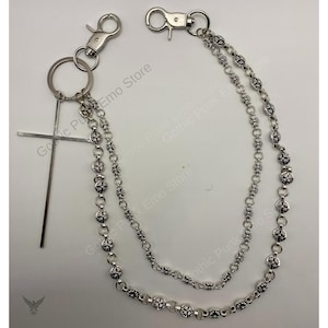 May include: Silver-toned chain accessory featuring two chains with decorative floral-like links. Includes a cross pendant and two clasp attachments. The accessory is designed for attaching to clothing or accessories.