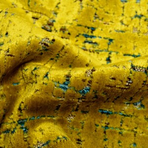 Puede incluir: Primer plano de una tela amarilla con un patr&oacute;n texturizado de l&iacute;neas azules y marrones. La tela tiene una textura suave y aterciopelada.