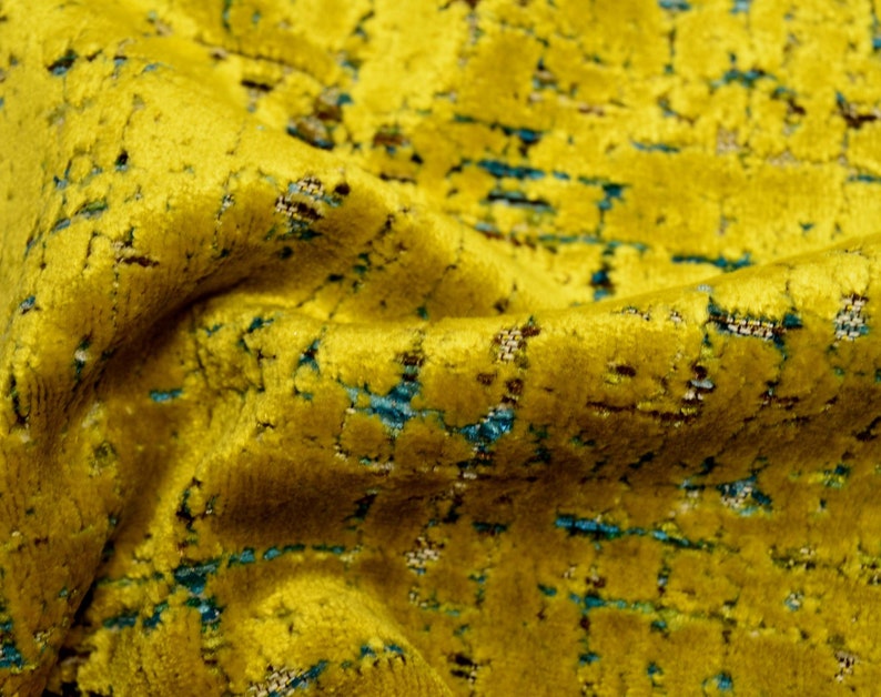 Puede incluir: Primer plano de una tela amarilla con un patr&oacute;n texturizado de l&iacute;neas azules y marrones. La tela tiene una textura suave y aterciopelada.