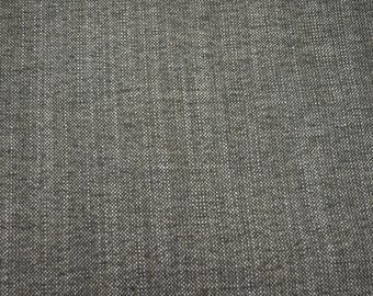 May include: A dark gray fabric with a visible woven texture. The material features a dense, interlaced pattern of dark gray and white threads, creating a consistent, speckled appearance across the entire surface of the textile material.
