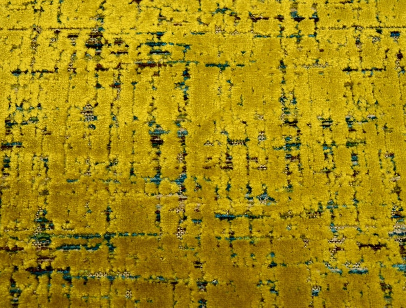 Puede incluir: Primer plano de una tela amarilla con un patr&oacute;n tejido texturizado. La tela tiene un sutil patr&oacute;n azul y marr&oacute;n tejido en el amarillo.