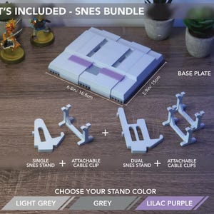 May include: A light grey SNES bundle with a base plate (6.6in x 5.9in), stands, and cable clips. The text "WHAT'S INCLUDED - SNES BUNDLE" is at the top. Choose from light grey, grey, or lilac purple.