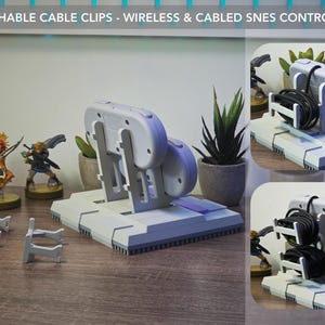 May include: A gray and purple SNES controller stand with attachable cable clips. The stand holds a wireless controller and has a base with a purple accent. The image also shows small figurines and potted plants.