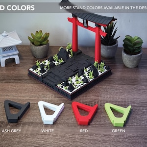 May include: A miniature Japanese Torii gate and pagoda model with a black base, red gate, and green accents. Four stand colors are displayed: ash grey, white, red, and green. The text "STAND COLORS" is visible.