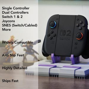 May include: Black Nintendo Switch controller with blue and red accents, resting on a gray and purple stand. The stand is designed to resemble a SNES console. Text on the controller reads "Nintendo Switch". The image also includes text indicating compatibility and features.