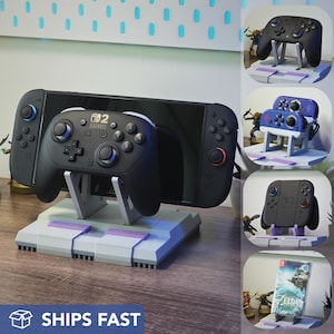 May include: A black Nintendo Switch console with a controller is displayed on a gray and purple stand. The stand has a retro design. Additional controllers and a game case are also shown.